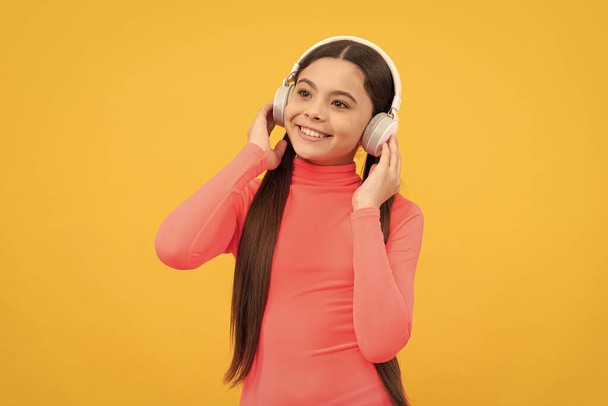 niño feliz escuchar música en auriculares sobre fondo amarillo, música. - Foto, Imagen