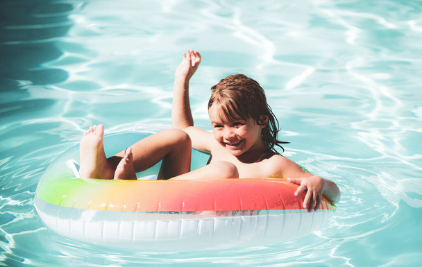 Children in swimming pool. Summer outdoor. Happy kid playing with colorful swim ring in swimming pool. Child water toys. Children play in tropical resort. Family beach vacation - Φωτογραφία, εικόνα