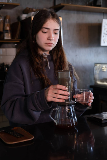 hübsches brünettes Mädchen macht Aeropress-Kaffee in modernem Café. - Foto, Bild