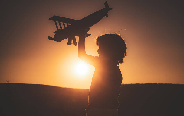 Child pilot aviator with airplane dreams of traveling on sunset - Foto, Imagem