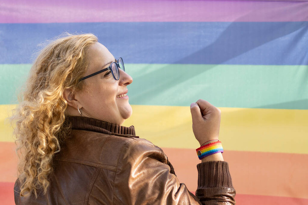 Портрет лесбиянки-латиноамериканки с браслетом на радужном фоне - Фото, изображение