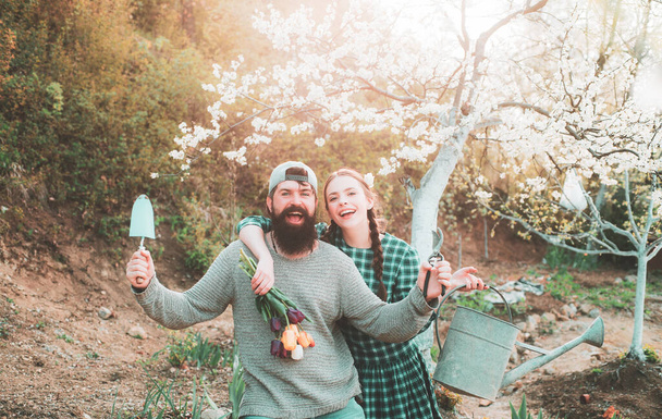 Funny gardener couple holding garden tools at spring nature background. Plants and gardening as spring hobby - Foto, imagen