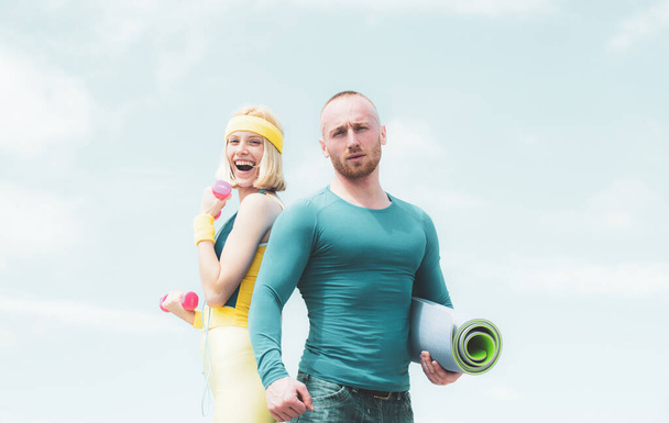Successful teamwork at blue sky background. Beautiful cheerful smiling woman workout with her sport coach. Loving couple doing fitness at fresh air outdoors - Photo, image
