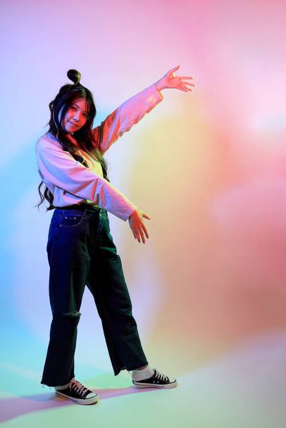 Söpö nuori aasialainen tyttö rento vaatteita poseeraa geelin väri salama studiossa. - Valokuva, kuva