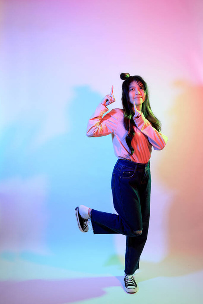Милая молодая азиатская девушка в повседневной одежде позирует под гелевым цветом молнии в студии. - Фото, изображение