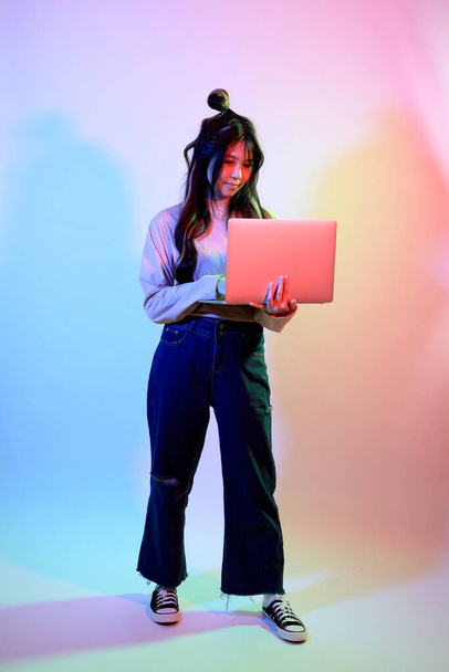 La giovane ragazza asiatica carina con vestiti casual in posa sotto il colore del gel fulmine in studio. - Foto, immagini