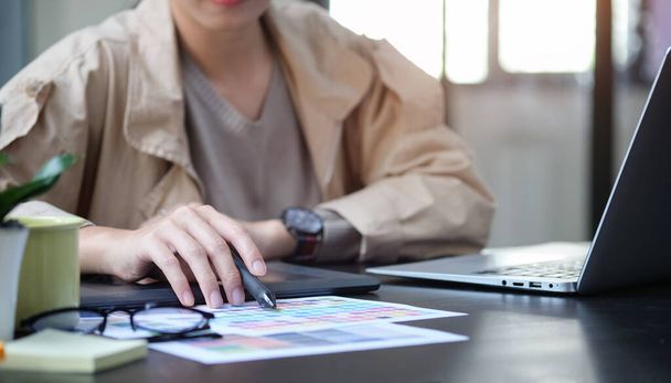 Kreativní mladá žena sedící na moderním pracovišti a pracující s barevnými hodinkami a notebookem. - Fotografie, Obrázek