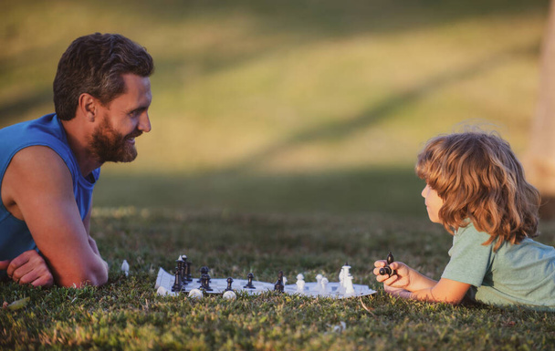 Father play chess with child son. Family outside game - Fotoğraf, Görsel