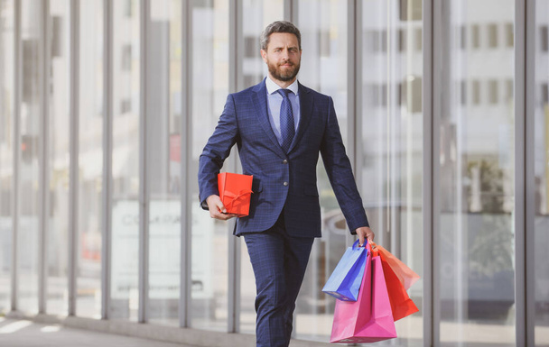 Business man holding shopping bags and walking in shopping store. Shopping and paying. Shopaholic shopping concept - Foto, afbeelding