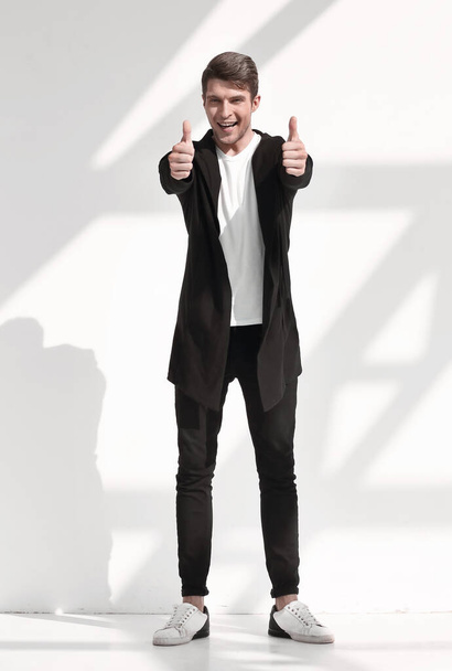 in full growth.smiling young man showing thumbs up.isolated on light background - Foto, Bild