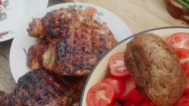 nóżka kurczaka w talerzu, obok patelni z sałatką z pomidorami i czarnym chlebem - Materiał filmowy, wideo