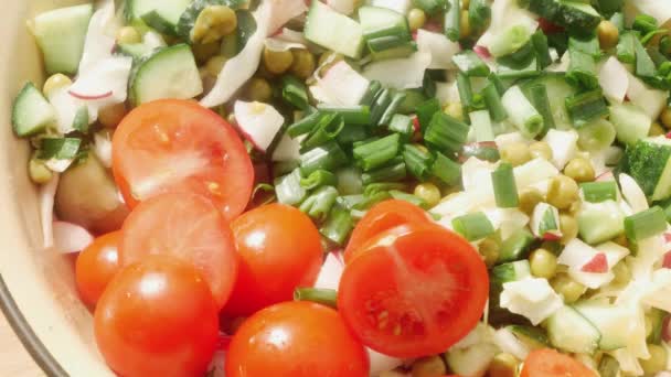  hand puts sliced tomatoes in spring salad, close-up - Footage, Video