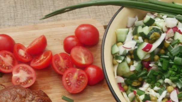 krájená rajčata, černý chléb a jarní salát, na dřevěné desce, detail. - Záběry, video