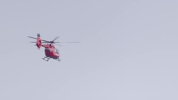 Ένα κόκκινο ελικόπτερο έκτακτης ανάγκης που πετάει στον ουρανό μια συννεφιασμένη μέρα. - Πλάνα, βίντεο
