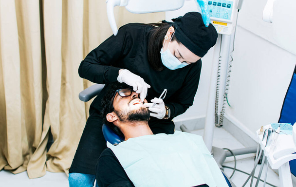 Tandarts uitvoeren van tandheelkundige controle, tandarts controleren beugels aan patiënt, patiënt gecontroleerd door tandarts - Foto, afbeelding