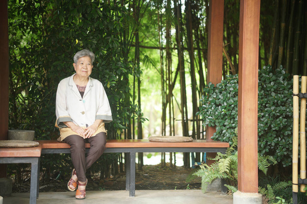 ηλικιωμένη ηλικιωμένη ηλικιωμένη ηλικιωμένη γυναίκα ξεκουράζεται καθισμένη στον κήπο - Φωτογραφία, εικόνα