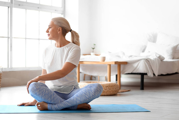 Morgen der reifen Frau praktiziert Yoga zu Hause - Foto, Bild