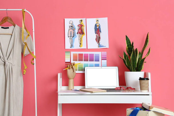 Робоче місце стиліста одягу біля рожевої стіни
 - Фото, зображення