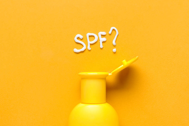 Bottle of sunscreen and question SPF? on color background - Foto, Imagem