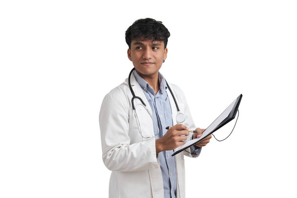 Jeune médecin péruvien qui rédige un rapport médical sur un dossier. Isolé sur fond blanc. - Photo, image
