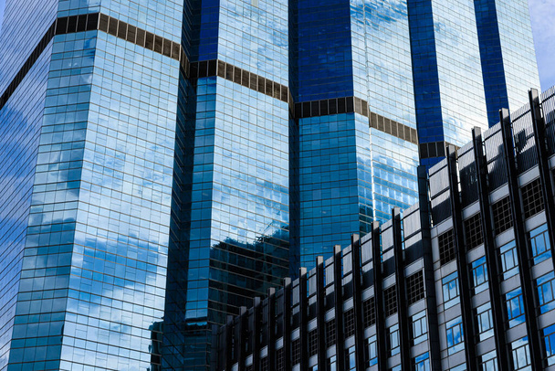 晴れた日に市内中心部のオフィスビルのガラスに反射した青い空と雲. - 写真・画像