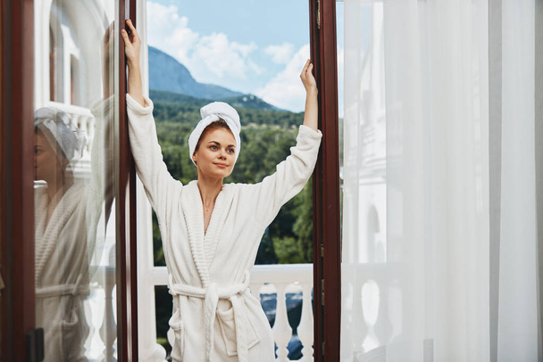 Atractiva mujer joven con una túnica blanca en el balcón poco en la naturaleza verde Mañana soleada perfecta. Foto de alta calidad - Foto, imagen