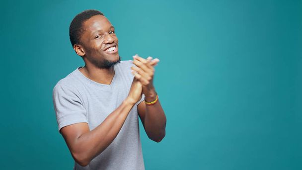 Pleased man applauding success and expressing admiration, showing approval and agreement with applause. Young adult clapping hands in front of camera, showing achievement support. - Photo, Image