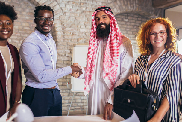 Multiculturele zakenmensen ontmoeten elkaar en praten over zaken. Arabische zakenman schudt handen met zijn zakenpartner. - Foto, afbeelding