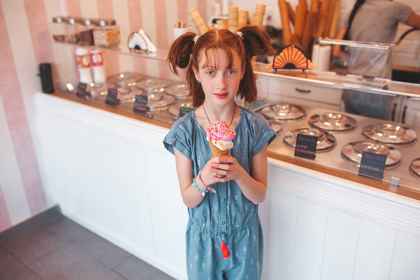 Nettes kleines Mädchen, das Eis in der Cafeteria isst. Kind hält Eis. Kind und Süßigkeiten - Foto, Bild