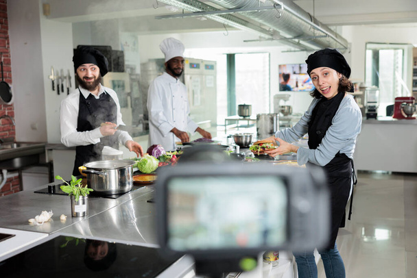 Gastronomy experts in restaurant professional kitchen cooking delicious gourmet dish for culinary school course. Cooks shooting video about food preparation process for gastronomic television show. - Photo, Image