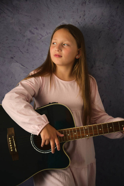 studio portret dziewczyny z czarną gitarą akustyczną w rękach - Zdjęcie, obraz