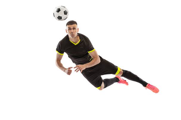 Head kick. Portrait of professional male football soccer player training isolated on white studio background. Concept of sport, goals, competition, hobby, ad. Sportsmen wearing black football kit - Photo, Image