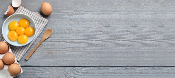 Fresh raw chicken eggs and spoon on grey wooden table, flat lay with space for text. Banner design - 写真・画像