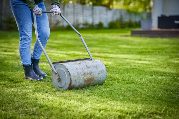 Woman working with lawn roller in the garden. High quality photo - Photo, Image