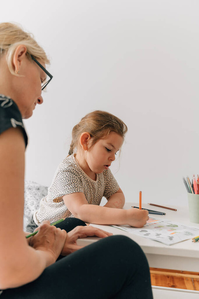 Mature woman granny with grandchild preschool girl drawing together at home. . High quality photo - Zdjęcie, obraz