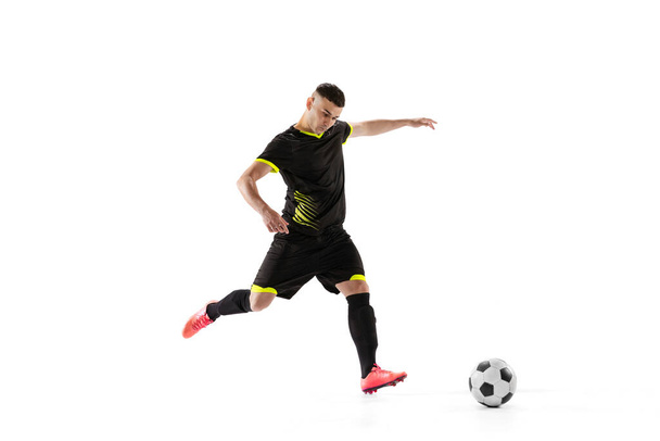 Professional male football soccer player in motion and action isolated on white studio background. Concept of sport, goals, competition, hobby, ad, world cup. Sportsmen wearing black football kit - Foto, Imagen