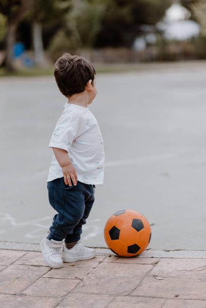 Küçük çocuk parkta bir futbol topuyla oynuyor, arkası dönük. Tanımlanamaz - Fotoğraf, Görsel