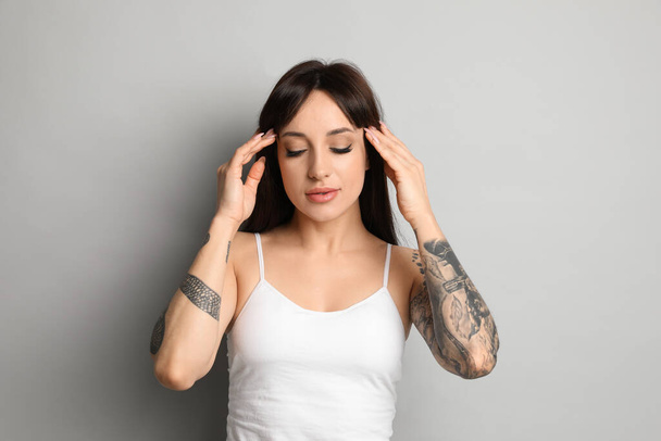 Beautiful woman with tattoos on arms against grey background - Fotó, kép
