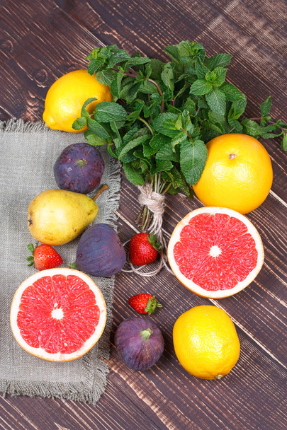 Grapefruits, pears, lemons, figs, strawberry, pomelo and mint on wooden background - Foto, Imagem