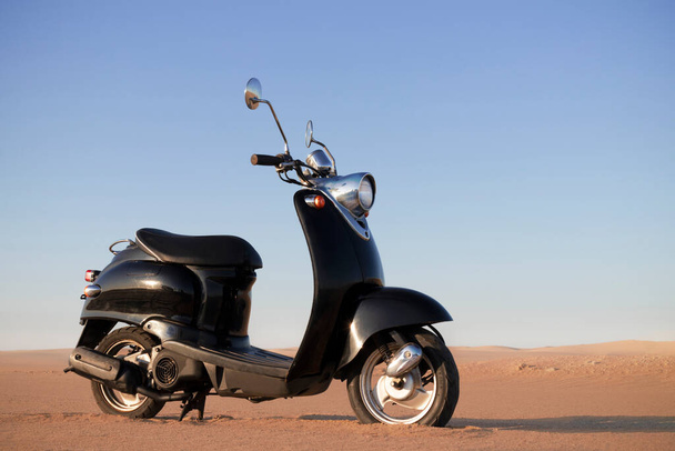 The Retro black scooter at sunset in the golden sand of the Namib Desert - Photo, Image