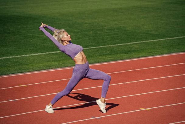 full of energy. athletic lady warming up on stadium running track. female athlete do sport workout. trainer or coach training. perfect body shape. healthy and sporty. sexy fitness woman in sportswear. - Foto, Imagem