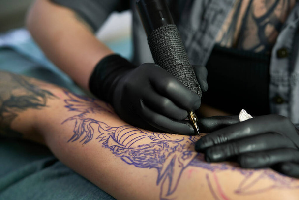 Primer plano del dibujo del artista del tatuaje en el brazo del cliente - Foto, Imagen
