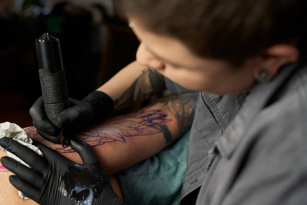 Gros plan du tatouage artiste dessin sur le bras du client - Photo, image