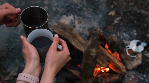 Couple in love Campsite With Fire Pit and Two Tin Cups with hot tea, coffee. Burning Campfire. - Fotó, kép
