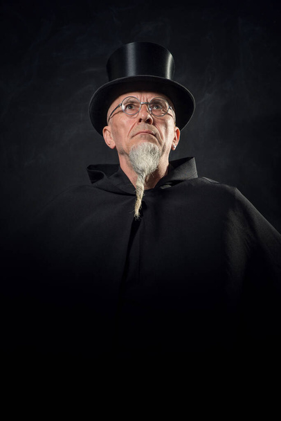 Portrait of a mysterious male magician in a black high top hat and black robe. - Photo, Image