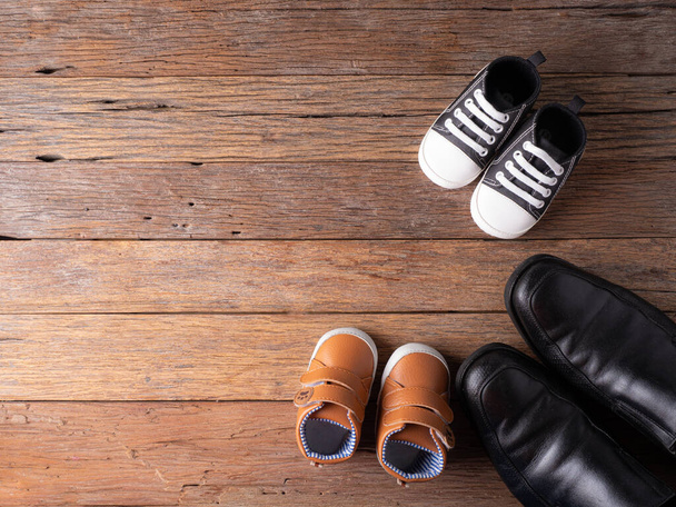 piękne dziecięce buty na drewnianym tle z butem ojca, przygotować się do koncepcji dziecka. - Zdjęcie, obraz