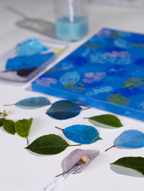 DIYアブストラクト植物画。この絵は、葉にアクリル絵具を塗り、キャンバスにスタンプすることで作られています。青で青. - 写真・画像