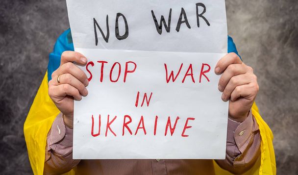 активист держит плакат с надписью "Нет войне на Украине" на публичной демонстрации. Мир Украине. Россия агрессору и международному теоретику - Фото, изображение