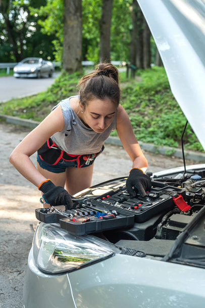 Krásná mladá žena otevřít kapotu a opravit auto na silnici. roztříštěné auto - Fotografie, Obrázek