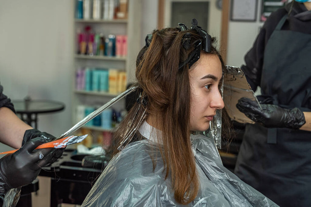 super cool stylist working on the image of a young girl in a beauty salon. The concept of hair coloring during quarantine in the salon - Photo, Image